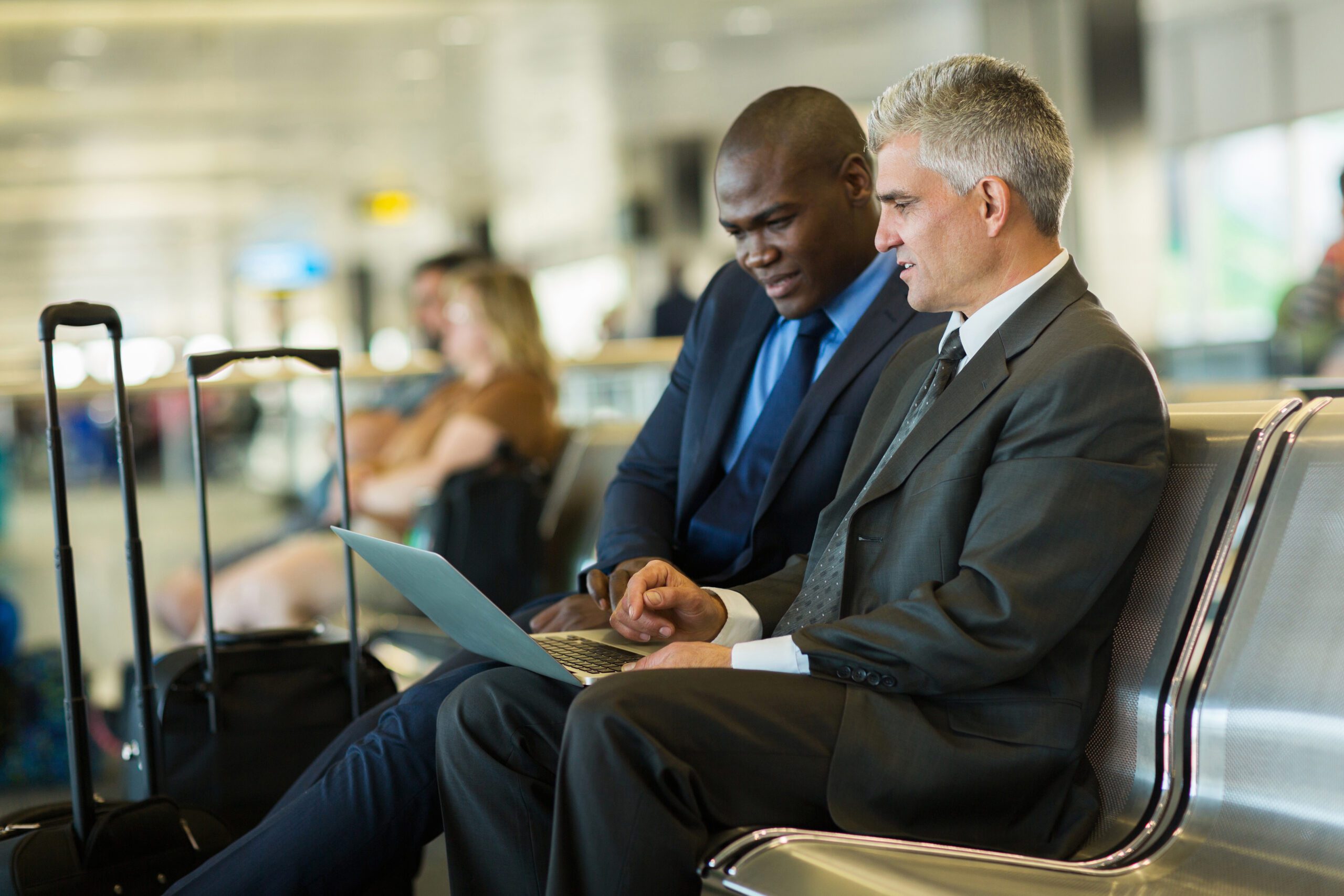 successful business travelers using laptop at airport